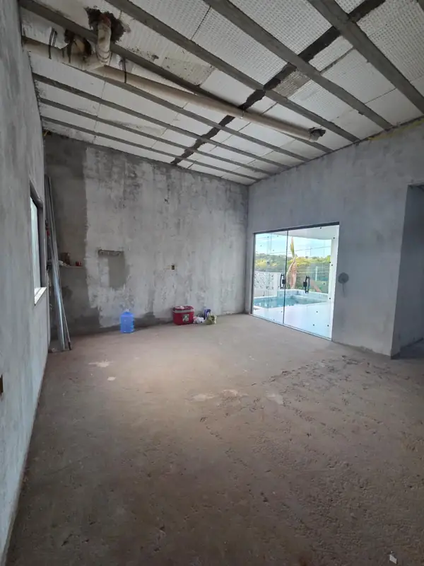 Sala de estar em obra cinza, com vista para a piscina
