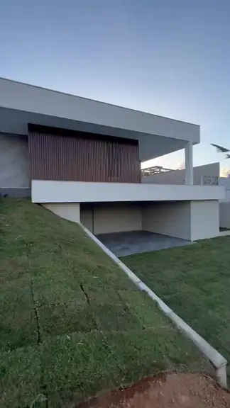 Lateral da casa com terreno em declive e área coberta no nível inferior