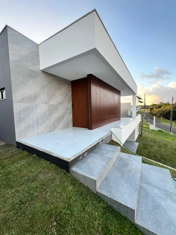 Fachada da casa com ripado de madeira, revestimento em pedra clara e escada de acesso